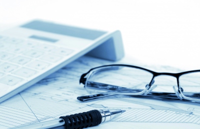 Paper, calculator, pen and glasses on table