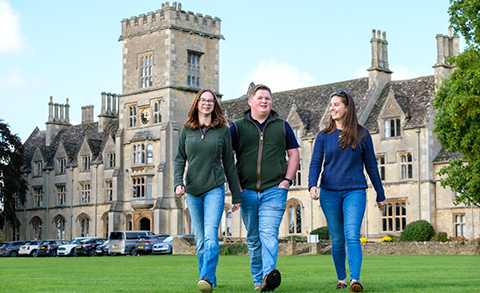 Three students walking on grass in front of RAU building