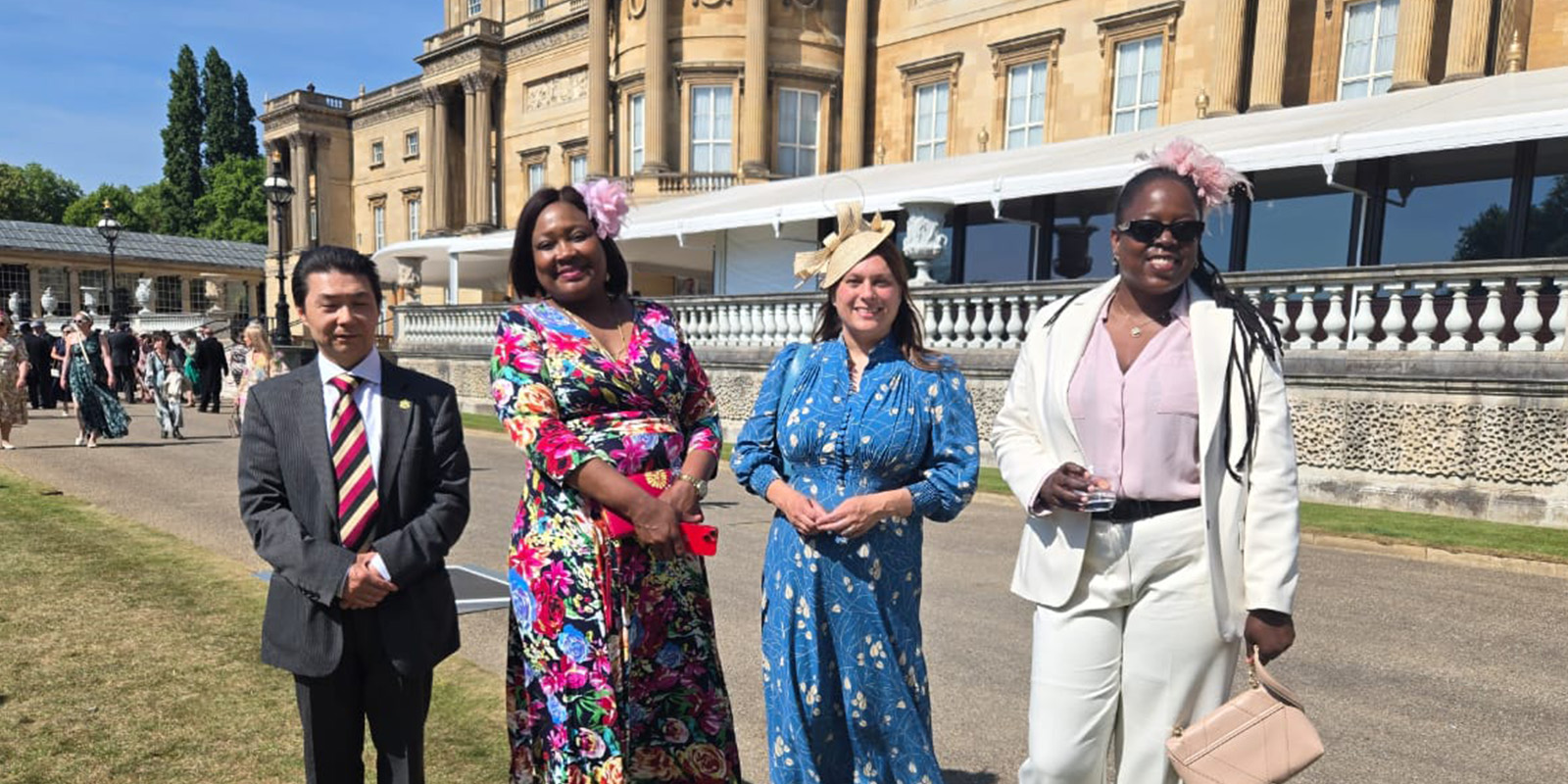 Four members of staff at a garden party in grounds of Buckingham Palace