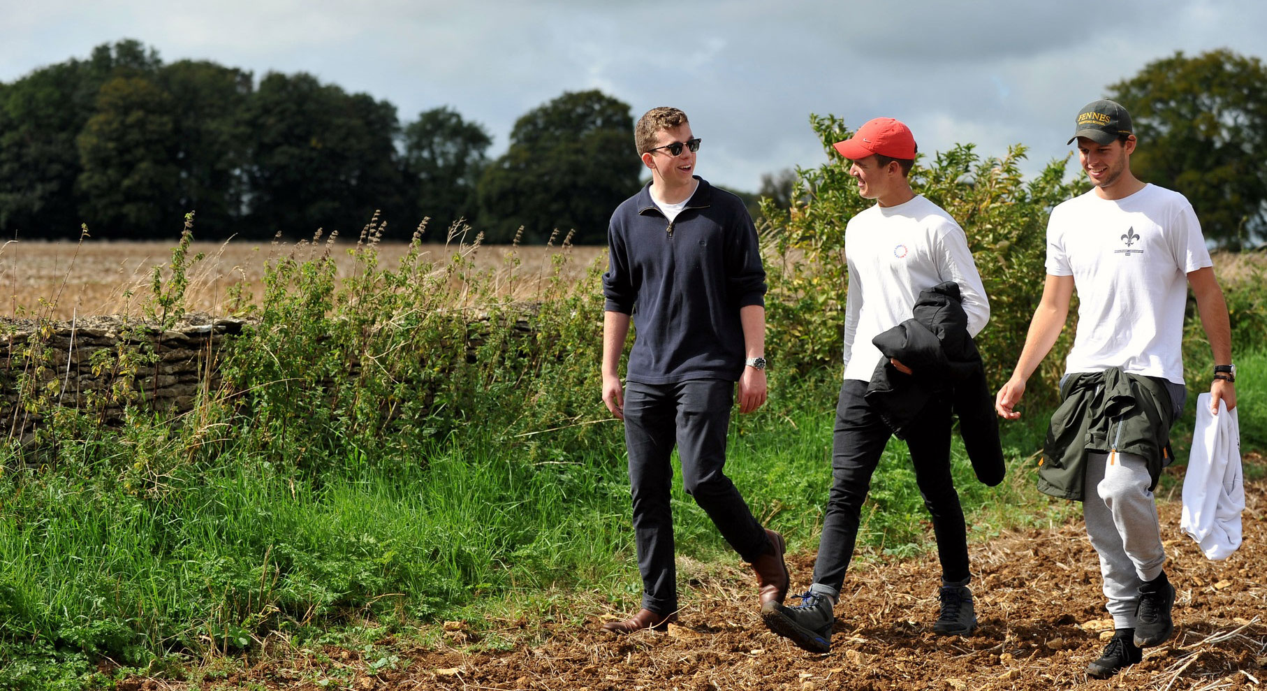 Three students walking across a field