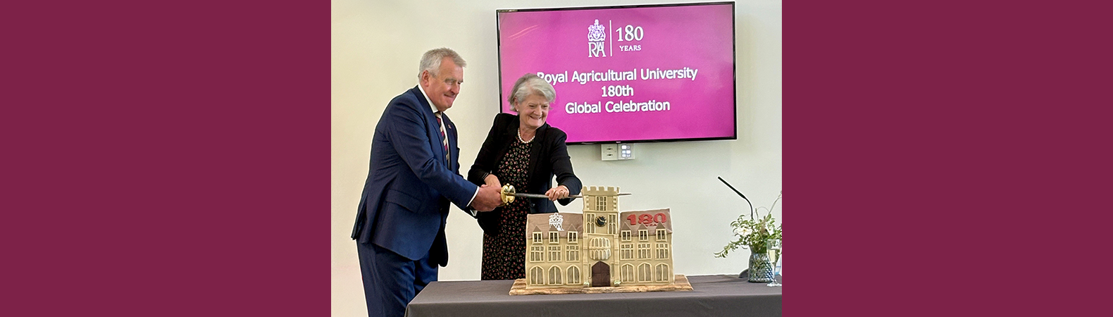 Professor Peter McCaffery and Dame Fiona Reynolds cutting a cake in the shape of the Royal Agricultural University at the 180th Anniversary Global Celebration