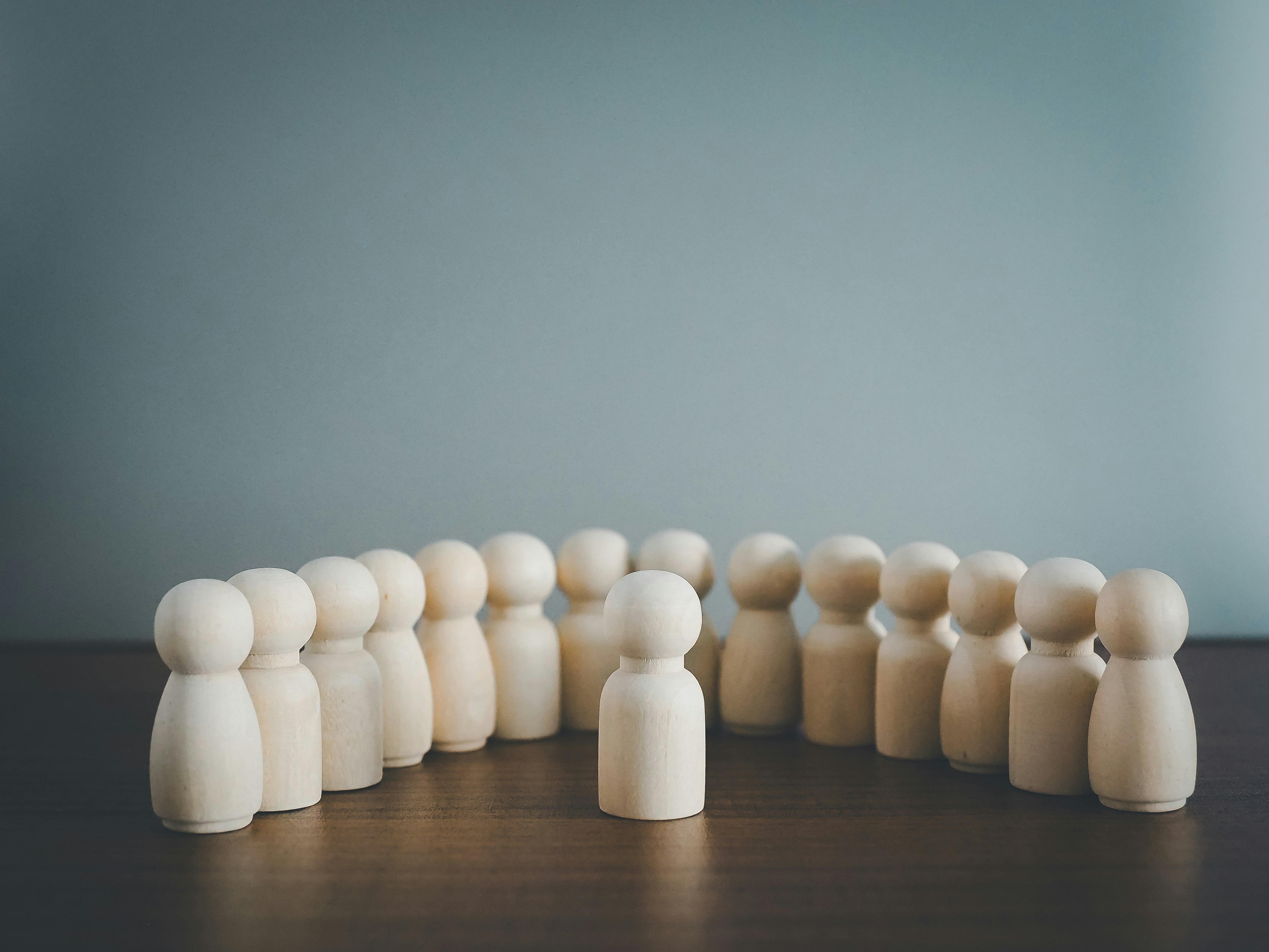 Wooden figures surrounding a single wooden figure