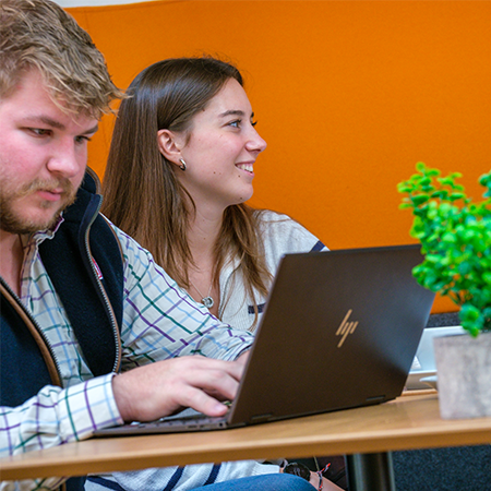 Students in a cafe, one is using a laptop
