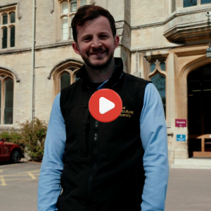 A member of staff standing in front of the Royal Agricultural University