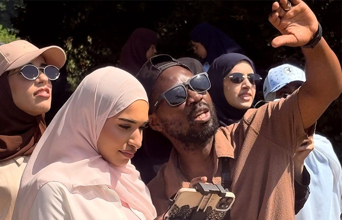 female student with phone looking at drone footage with male teacher looking up at drone