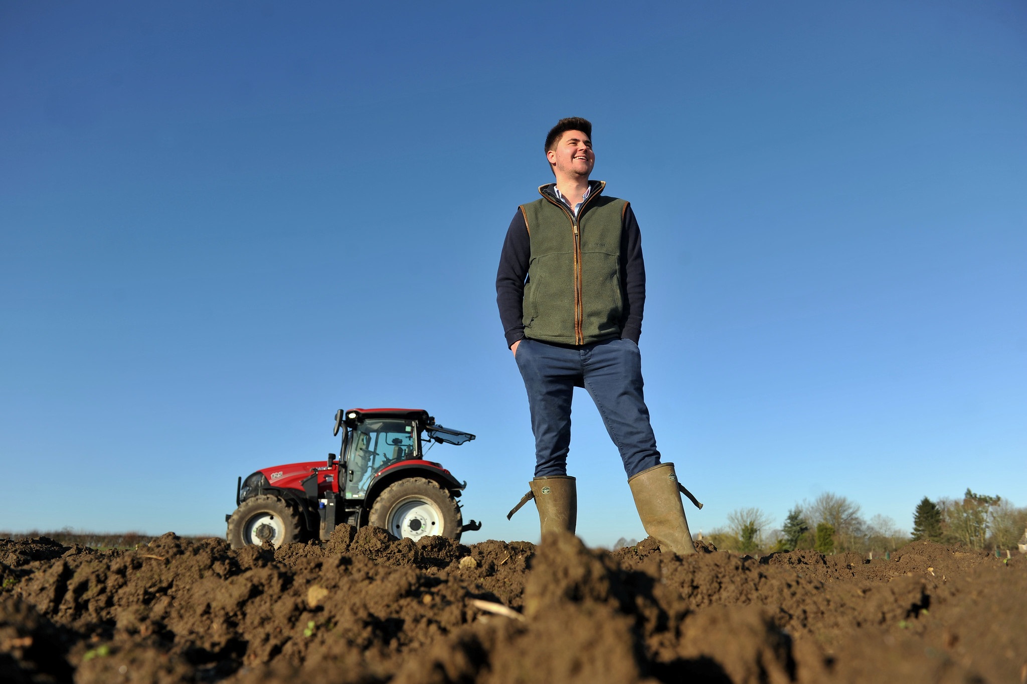 Student standing in a field with a tractor