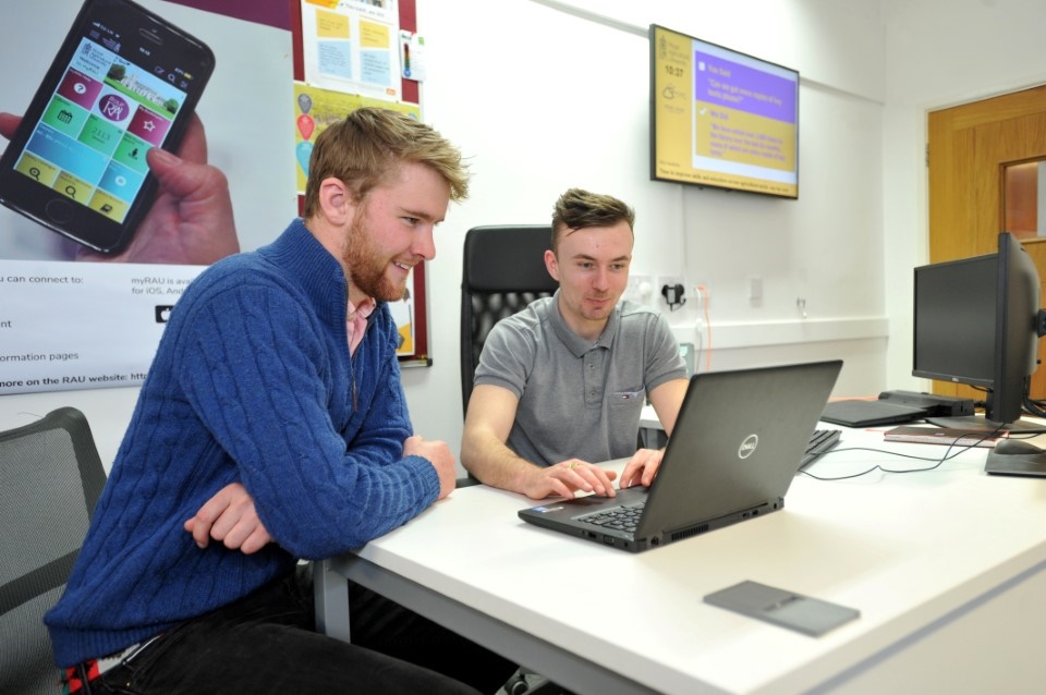 Student and staff member looking at laptop