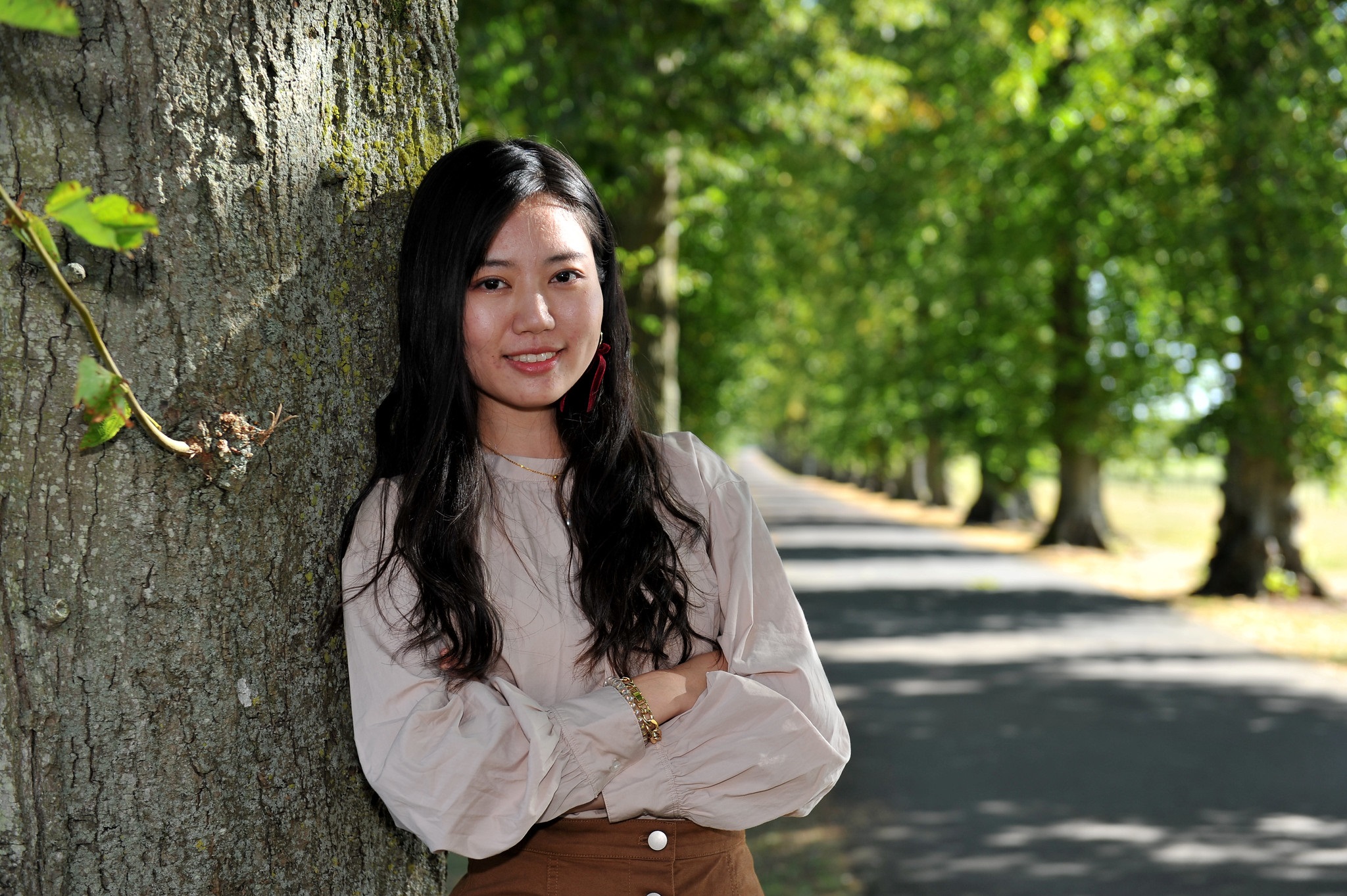 Student leaning against a tree