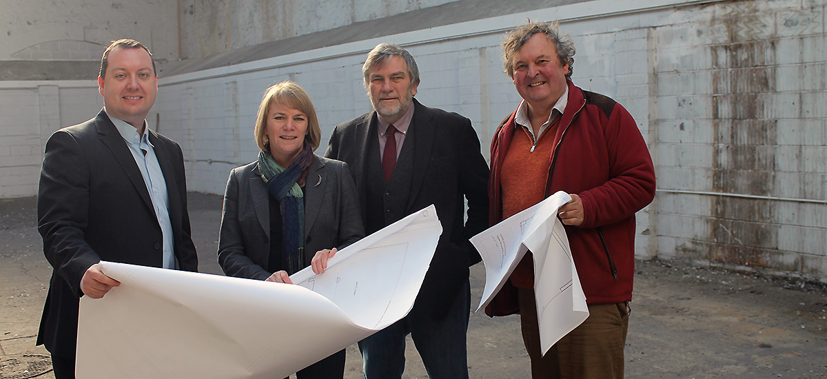 Image of team in the empty building reviewing a set of plans
