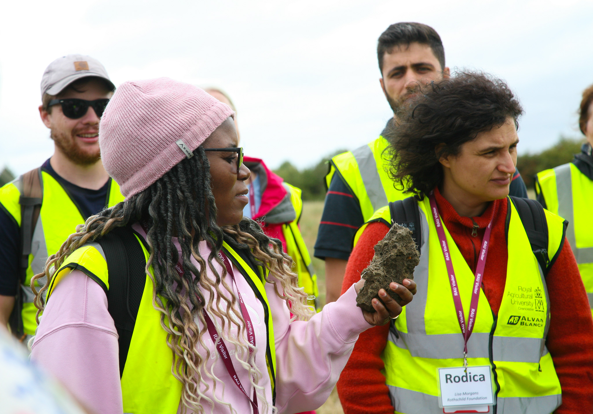 Delegates in a field, with one person holding a chunk of hard soil