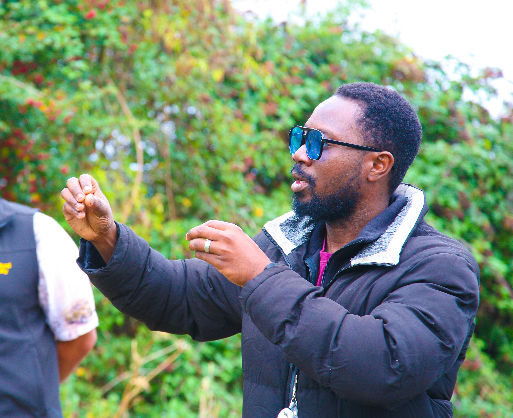 A man explaining a concept with hand gestures in an outside environment