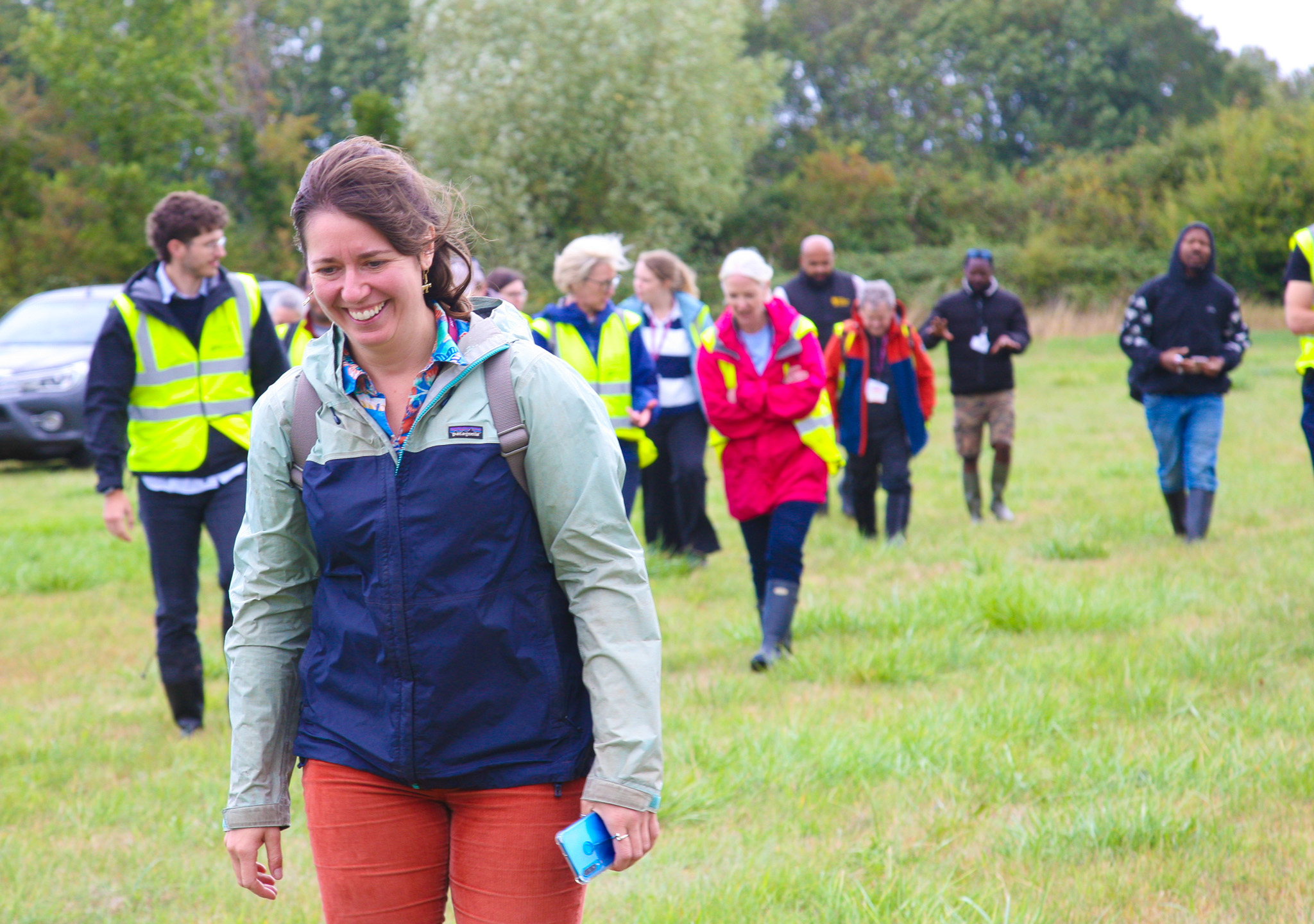 A woman in a coat walking over a field with people following behind