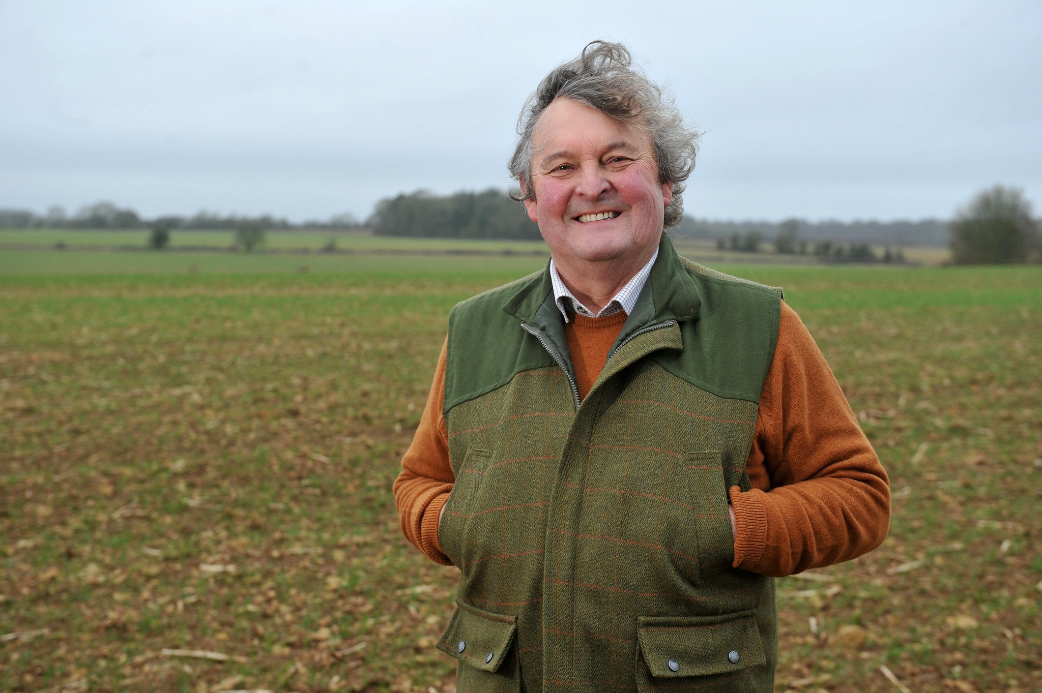 Man standing in front of field with hands in gilet pockets