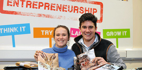 two students holding branded merchandise