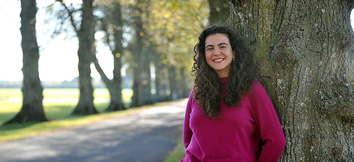 Student leaning against a tree