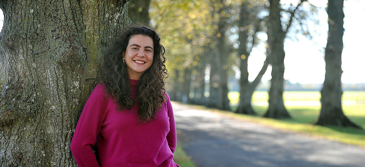 Student leaning against a tree