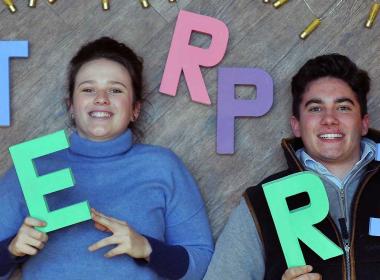 Two students holding enterprise letters