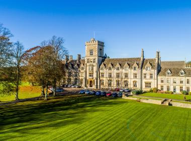 A photograph of the Royal Agricultural University main building on a sunny day with a blue sky. 
