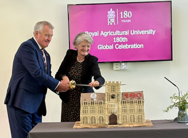Professor Peter McCaffery and Dame Fiona Reynolds cutting a cake in the shape of the Royal Agricultural University at the 180th Anniversary Global Celebration